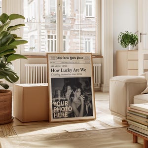 K&ouml;nnte beinhalten: Ein Zeitungs-Mockup im Vintage-Stil mit der Schlagzeile "How Lucky Are We" und dem Text "Creating memories since 2022". Die Zeitung zeigt ein Schwarzwei&szlig;foto von zwei Personen in einer schwach beleuchteten Umgebung. Der Text "YOUR PHOTO HERE" ist &uuml;ber das Foto gelegt.