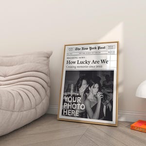 K&ouml;nnte beinhalten: Ein Schwarzwei&szlig;-Zeitungsdruck mit der Schlagzeile "How Lucky Are We" und dem Text "Creating memories since 2022". Die Zeitung ist gerahmt und hat ein Foto von zwei Frauen in der unteren H&auml;lfte. Der Text "YOUR PHOTO HERE" ist in der Mitte des Fotos gedruckt.