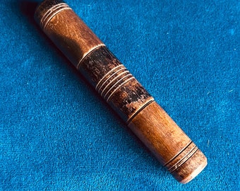 May include: A wooden thimble with a dark brown stain and decorative grooves. The thimble is on a blue surface.