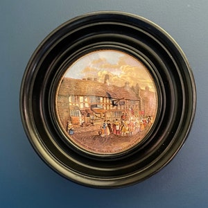 Pode incluir: Uma imagem redonda emoldurada em preto que representa uma cena pintada de um edifício com pessoas na frente. O texto na parte inferior diz "Shakespeare's House Henley St. Stratford-Avon".