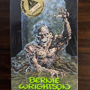 May include: A box for a set of trading cards featuring a green and black illustration of a zombie-like creature emerging from the ground. The box has a gold circle with the text "Bernie Wrightson Master of the Macabre" and the number "32430 of 90,000 Boxes".