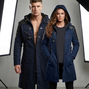 May include: Two people wearing navy blue hooded coats with black leather shoulder detailing. The coats feature metal clasps and pockets. The person on the left is wearing the coat open, while the person on the right has the coat zipped up.