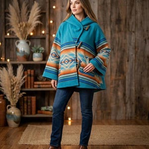 May include: A turquoise hooded coat with a Southwestern-inspired pattern in orange, blue, and cream. The coat features wooden toggle closures and is paired with dark blue jeans and brown boots. The background includes a wooden bookshelf and decorative elements.