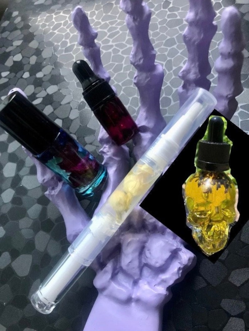 Peut inclure: Trois flacons en verre avec des compte-gouttes, un transparent avec une substance blanche, un violet avec un liquide fonc&eacute; et un flacon en forme de cr&acirc;ne avec un liquide jaune. Les flacons sont sur un objet en forme de main violet.
