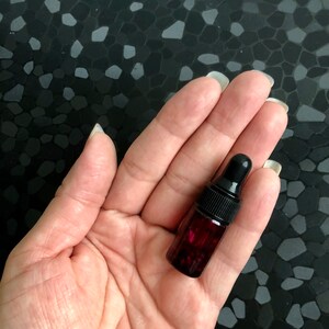 Peut inclure: Un petit flacon en verre rouge fonc&eacute; avec un compte-gouttes noir. Le flacon est rempli d'un liquide rouge fonc&eacute;.