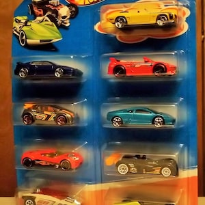 Könnte beinhalten: Ein 9er-Pack Hot Wheels-Spielzeugautos aus Druckguss in verschiedenen Farben und Stilen. Die Autos sind auf einer Pappverpackung mit dem Hot Wheels-Logo und dem Schriftzug "9-Pack" abgebildet.