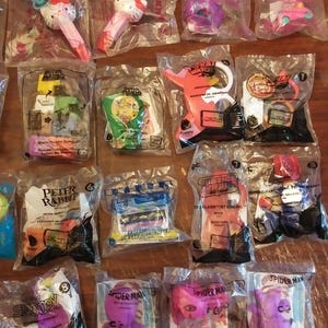 Puede incluir: Una colecci&oacute;n de juguetes de pl&aacute;stico coloridos empaquetados en bolsas de pl&aacute;stico transparentes. Los juguetes incluyen personajes de franquicias populares como Super Mario, Spider-Man y Hello Kitty. Los juguetes est&aacute;n dise&ntilde;ados para ni&ntilde;os y es probable que se regalen como parte de una campa&ntilde;a promocional.