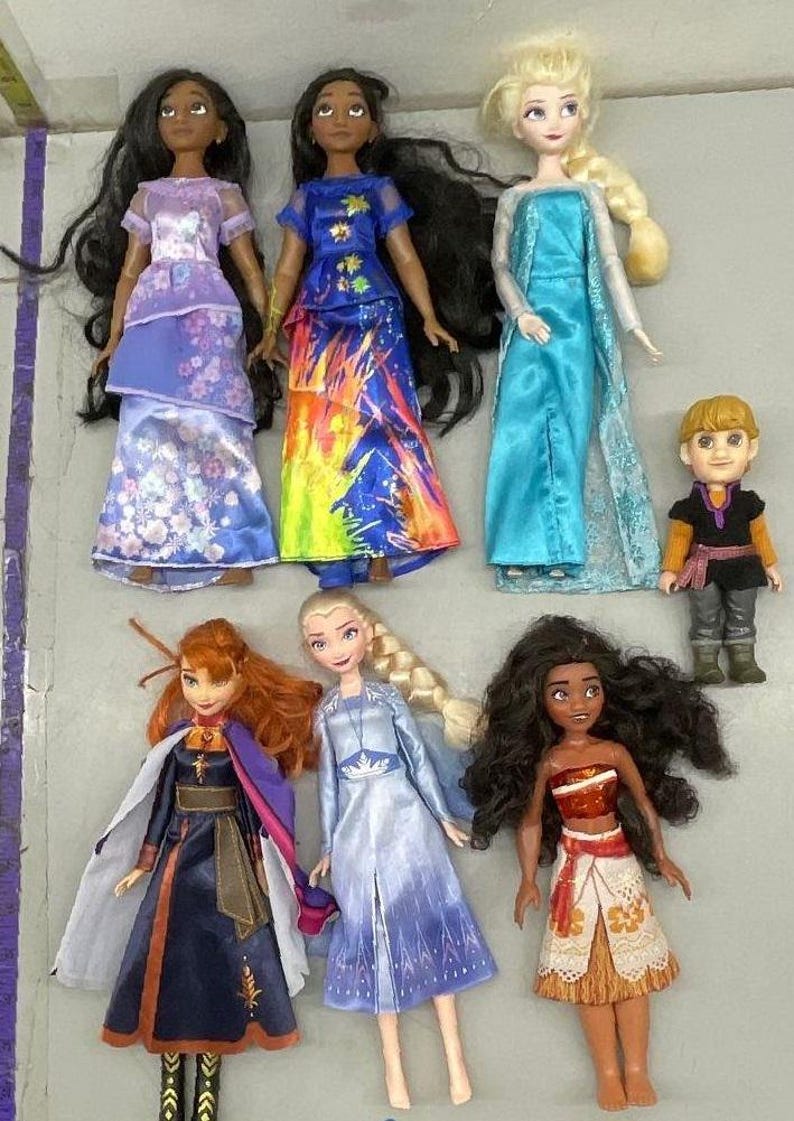 Puede incluir: Una colecci&oacute;n de siete mu&ntilde;ecas de princesas Disney, incluyendo Elsa, Anna, Moana y dos versiones de Pocahontas. Las mu&ntilde;ecas llevan todas sus atuendos caracter&iacute;sticos y tienen el pelo largo y suelto.