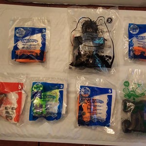 Może przedstawiać: Kolekcja dziesięciu opakowań zabawek Hot Wheels, z r&oacute;żnymi wzorami i kolorami. Opakowanie wykonane jest z plastiku i zawiera r&oacute;żne grafiki, w tym samochody, ciężar&oacute;wki i inne pojazdy. Opakowanie jest oznaczone logo Hot Wheels i słowami "Prototype Plus".