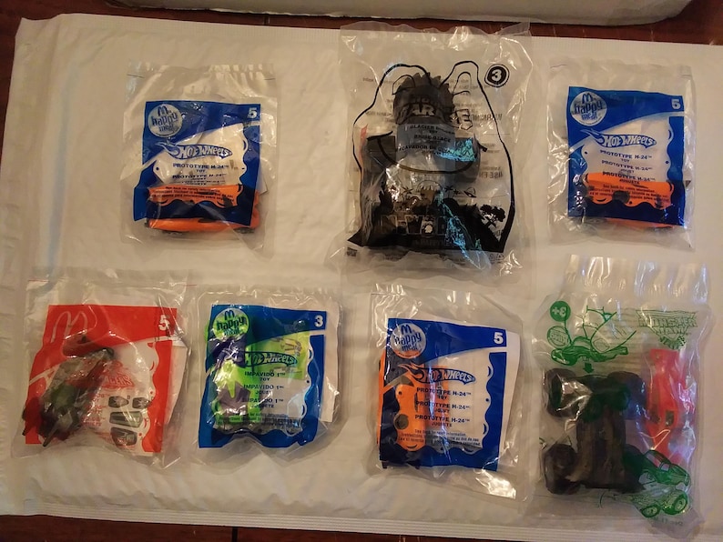 Może przedstawiać: Kolekcja dziesięciu opakowań zabawek Hot Wheels, z r&oacute;żnymi wzorami i kolorami. Opakowanie wykonane jest z plastiku i zawiera r&oacute;żne grafiki, w tym samochody, ciężar&oacute;wki i inne pojazdy. Opakowanie jest oznaczone logo Hot Wheels i słowami "Prototype Plus".