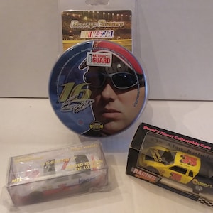 May include: Three NASCAR themed collectibles: a round beverage coaster featuring a photo of Alan Kulwicki with the text "National Guard" and "16", a small yellow die-cast car with the number "35" and the text "Quincy's", and a white die-cast car with the number "7" and the text "Hanes".