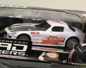 May include: A white radio-controlled toy car with black and red details. The car is labeled "PowerX" and "80". The box is labeled "Rad Racers Speed Series" and "Wham-O 1:22 Scale".