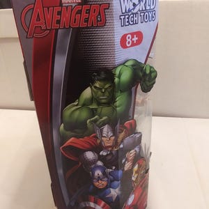 May include: A red, white and black box with the Marvel Avengers logo and the World Tech Toys logo. The box features images of Hulk, Thor, Captain America and Iron Man. The box is labelled 8+ and has a warning label.