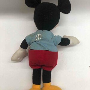 Puede incluir: Un juguete de peluche vintage de Mickey Mouse con orejas negras, cabeza negra, camisa azul con un c&iacute;rculo blanco, pantalones cortos rojos y zapatos amarillos.