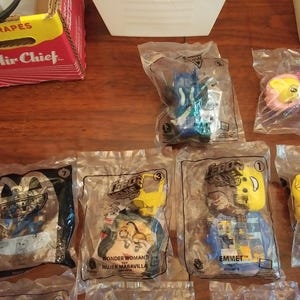 Puede incluir: Una colecci&oacute;n de bolsas de pl&aacute;stico que contienen peque&ntilde;os juguetes de la pel&iacute;cula Lego 2. Los juguetes son de varios colores, incluyendo azul, amarillo y rojo. Las bolsas est&aacute;n etiquetadas con los nombres de los personajes, incluyendo Wonder Woman, Emmet y Unikitty.
