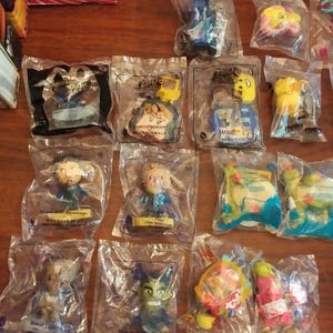 Puede incluir: Una colecci&oacute;n de 12 figuras de juguete de pl&aacute;stico de la pel&iacute;cula Lego 2, empaquetadas individualmente en bolsas de pl&aacute;stico transparentes. Las figuras incluyen personajes como Batman, Wonder Woman, Emmet y Unikitty. Cada bolsa presenta un dise&ntilde;o colorido con el logotipo de la pel&iacute;cula Lego 2.