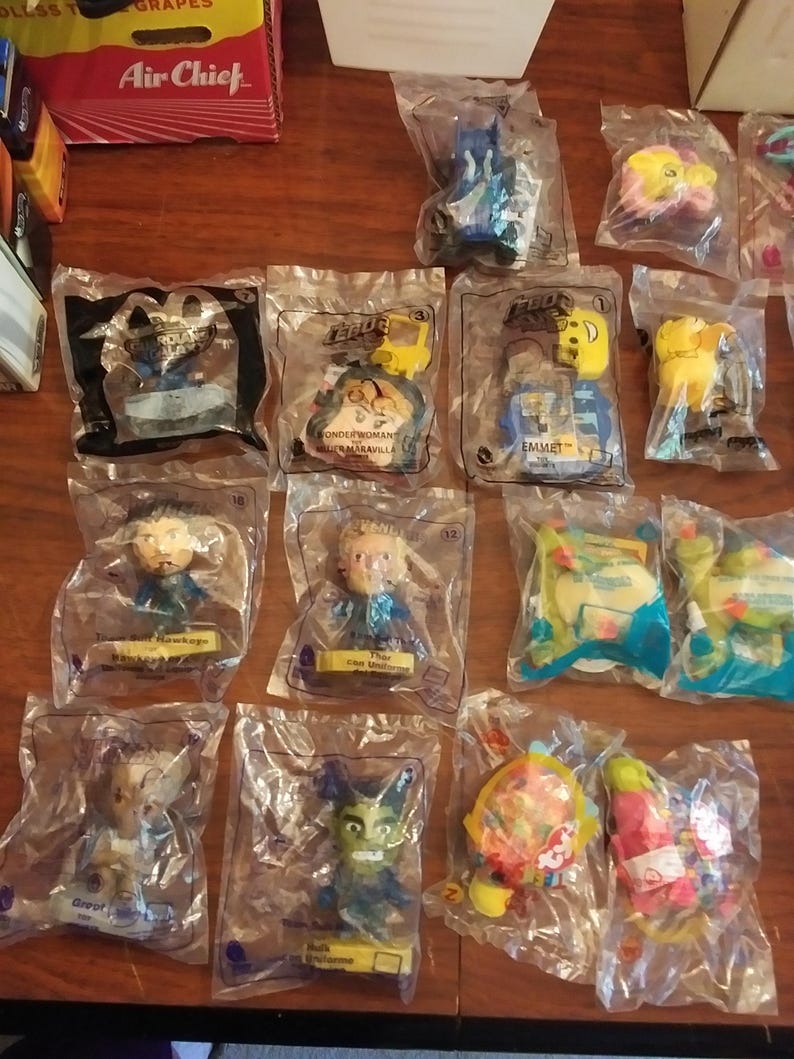 Puede incluir: Una colecci&oacute;n de 12 figuras de juguete de pl&aacute;stico de la pel&iacute;cula Lego 2, empaquetadas individualmente en bolsas de pl&aacute;stico transparentes. Las figuras incluyen personajes como Batman, Wonder Woman, Emmet y Unikitty. Cada bolsa presenta un dise&ntilde;o colorido con el logotipo de la pel&iacute;cula Lego 2.