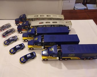 May include: A set of nine toy race cars, including a blue and yellow semi-trailer truck with a flatbed trailer, and eight blue and yellow race cars. The semi-trailer truck has a white and yellow design with the words "NASCAR" and "94" on the side. The race cars have the number "94" on the side.
