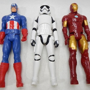 May include: Three action figures: Captain America in a blue and red suit, a white Stormtrooper, and Iron Man in a red and gold suit.