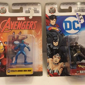 May include: Two Nano Metalfigs action figures, one Marvel Avengers Stealth Armor Iron Man and one DC Batman. The figures are in clear plastic packaging attached to colorful cardboard backings. The Marvel figure is blue, and the DC figure is black and gray.