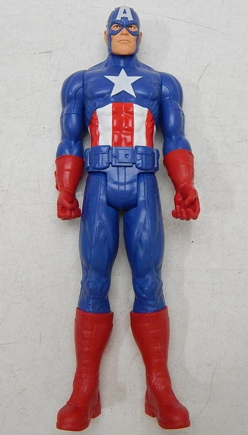 May include: A blue and red plastic action figure of Captain America. The figure has a red, white, and blue costume with a star on the chest. The figure is standing with its arms at its sides.