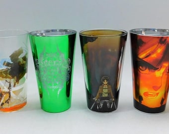 May include: Six different glass tumblers with various graphic designs. The tumblers are clear glass with colorful graphics. The designs include a dice with the word "FAIL", a scene with a knight, a green design with a dragon, a scene with a character from the anime Attack on Titan, a scene with a character from the anime My Hero Academia, and a blue robot.