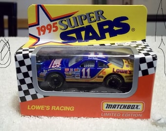 May include: A blue and yellow Matchbox 1995 Super Stars limited edition die-cast car with the number 11 on the side and Lowe's branding. The car is in a clear plastic case with a checkered background.