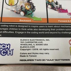 Puede incluir: Un kit de robot de codificaci&oacute;n Teach Tech con un robot verde y naranja, un port&aacute;til azul y blanco y un bloque azul. La caja tiene el texto "Teach Tech" y "Requires Two (2) "AAA" Batteries".