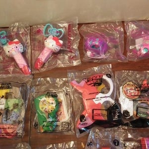 Puede incluir: Surtido de envases de personajes de juguetes coloridos, incluyendo Super Mario, Yo-Kai Watch y Hello Kitty. Los envases son de pl&aacute;stico transparente y presentan varios personajes y logotipos.