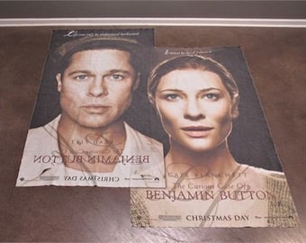 May include: Two movie posters for the film "The Curious Case of Benjamin Button" featuring Brad Pitt and Cate Blanchett. The posters are both white with black text and feature the film's title and release date.