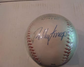 May include: A white baseball with red stitching and a blue signature that reads "Roddy Knapp" and the date "5/14/80" written in black ink.