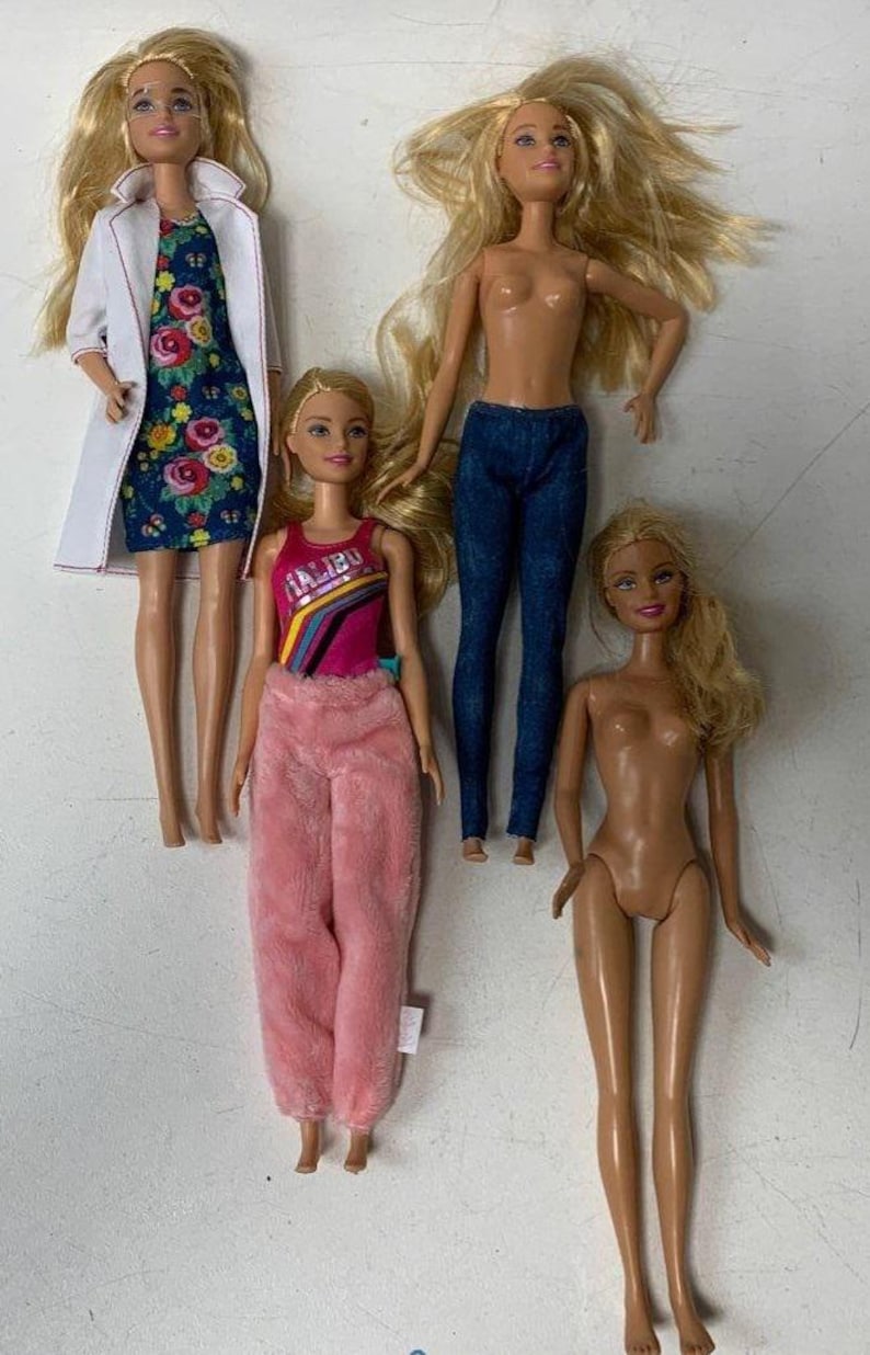 May include: Four blonde Barbie dolls with different outfits. One doll is wearing a white lab coat over a floral dress, another is wearing a pink fuzzy pajama top and pants, another is wearing a blue tank top with the word "Malibu" on it and blue jeans, and the last doll is nude.