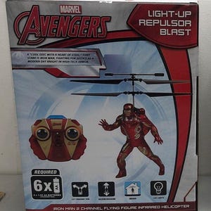 May include: A red and gold Iron Man flying figure infrared helicopter toy with a light-up repulsor blast. The box shows a red and gold remote control and the text "A 'cool exec with a heart of steel' - Tony Stark is Iron Man, fighting for justice as a modern day knight in high-tech armor."  The box also says "Required 6x 1.5V AA batteries".