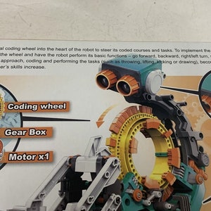 Puede incluir: Un robot de juguete verde, amarillo y naranja con una rueda de codificaci&oacute;n. La rueda de codificaci&oacute;n es un engranaje circular con una serie de botones que se pueden usar para programar el robot. El robot tambi&eacute;n tiene una caja de engranajes y un motor. El texto en la imagen dice: "Coloque la rueda de codificaci&oacute;n mec&aacute;nica en el coraz&oacute;n del robot para dirigir sus cursos y tareas codificados. Para implementar los c&oacute;digos, encaje los botones de codificaci&oacute;n en la rueda y haga que el robot realice sus funciones b&aacute;sicas: avanzar, retroceder, girar a la derecha/izquierda, girar o pausar. Gracias a este enfoque f&aacute;cil de seguir, la codificaci&oacute;n y la realizaci&oacute;n de las tareas (como lanzar, levantar, patear o dibujar) se vuelven m&aacute;s interesantes y desafiantes a medida que las habilidades del usuario aumentan. Bater&iacute;a AAA (no incluida)"