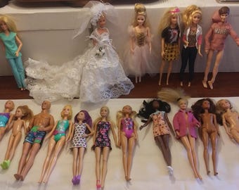 May include: A collection of 18 dolls, some wearing dresses, others in swimsuits, and some in casual clothing. The dolls are arranged in two rows on a white surface.