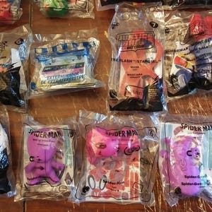 Puede incluir: Una colecci&oacute;n de ocho bolsas de pl&aacute;stico que contienen varios juguetes y art&iacute;culos promocionales. Las bolsas presentan personajes de pel&iacute;culas y programas de televisi&oacute;n populares, incluyendo Peter Rabbit, la Liga de la Justicia, Superman, Wonder Woman y Spider-Man. Los juguetes est&aacute;n empaquetados en bolsas de pl&aacute;stico transparentes con gr&aacute;ficos y texto coloridos.