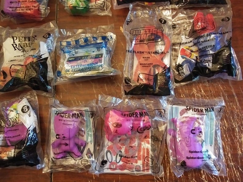 Puede incluir: Una colecci&oacute;n de ocho bolsas de pl&aacute;stico que contienen varios juguetes y art&iacute;culos promocionales. Las bolsas presentan personajes de pel&iacute;culas y programas de televisi&oacute;n populares, incluyendo Peter Rabbit, la Liga de la Justicia, Superman, Wonder Woman y Spider-Man. Los juguetes est&aacute;n empaquetados en bolsas de pl&aacute;stico transparentes con gr&aacute;ficos y texto coloridos.