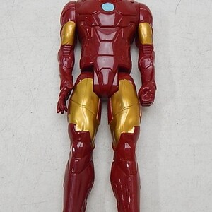 May include: Red and gold plastic action figure of Iron Man. The figure has a red and gold suit with a blue arc reactor on the chest.
