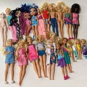 May include: A collection of 19 dolls, including Barbie dolls, fashion dolls, and other dolls. The dolls are dressed in a variety of colorful outfits, including dresses, skirts, pants, and shirts. Some dolls have long hair, while others have short hair. The dolls are all standing on a white surface.