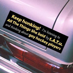 以下が含まれることがあります： 銀色の車に貼られた黒い長方形のステッカー。テキストは「Keep honking! I'm listening to All The Things She Said by t.A.T.u. and thinking about gay hockey players.」と書かれています。