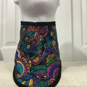 May include: A colorful dog collar with a black trim. The collar features a vibrant floral pattern in shades of blue, purple, orange, yellow, and green on a black background. The collar is displayed on a white mannequin head.