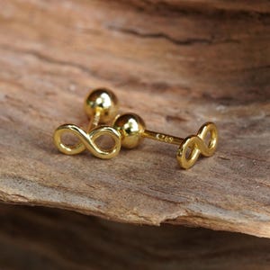 Op de afbeelding: Een paar gouden oorringen met een oneindigheidssymbool. De oorringen zijn klein en delicaat en perfect voor dagelijks gebruik.