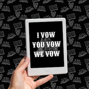 Op de afbeelding: Een witte Kindle e-reader met een zwart scherm waarop de tekst "I Vow You Vow We Vow" in witte letters wordt weergegeven. De tekst is gecentreerd op het scherm en lijkt een huwelijksgelofte te zijn.