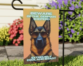 May include: A garden flag with a cartoon German Shepherd wearing sunglasses. The flag reads "Beware of the German Shepherd Extremely Cool and Shady".