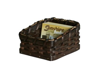 May include: A dark brown woven basket with a magazine inside. The magazine has the text "Sunshine Baskets" on the cover.