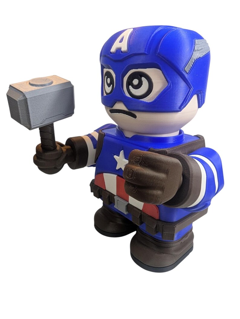 May include: A blue and white Captain America figurine holding a silver hammer. The figurine has a blue helmet with the letter "A" on the forehead, a star on the chest, and a red, white, and blue belt. The figurine is a collectible item.