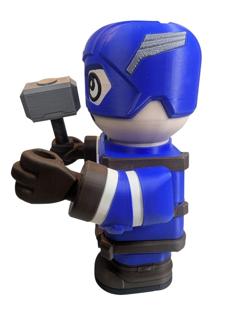 May include: A blue and white figurine of a superhero holding a gray hammer. The figurine has a blue helmet with white accents and a blue uniform with white stripes. The figurine is a toy.