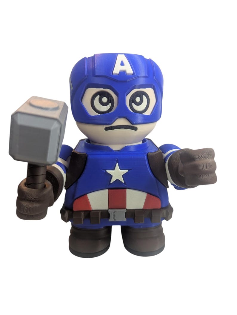 May include: A blue and red Captain America figurine holding a gray hammer. The figurine has a blue helmet with a white "A" on the forehead, a white star on the chest, and a red and white belt. The figure is in a cartoon style.