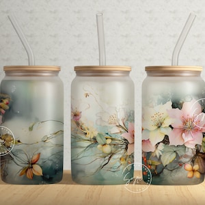 May include: Three frosted glass tumblers with bamboo lids and clear straws. Each tumbler features a watercolor floral design in shades of pink, yellow, and teal. The floral design includes branches and leaves.