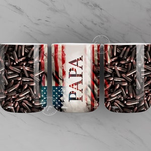 Pode incluir: Três canecas de cerâmica branca com tema patriótico. As canecas apresentam um design de bandeira americana com a palavra "PAPA" no centro. As canecas são decoradas com um padrão de balas marrons.